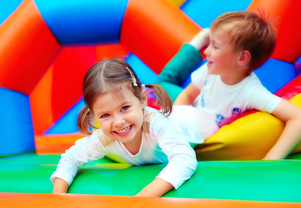 happy little kids smiling in a colorful bounce house rental at a backyard party